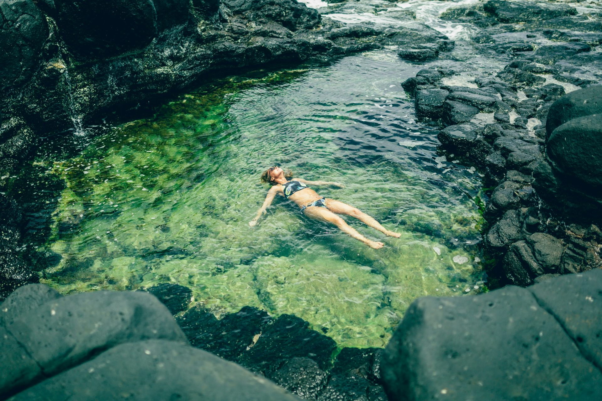 A guest floating on their back in a clear, calm rock pool
