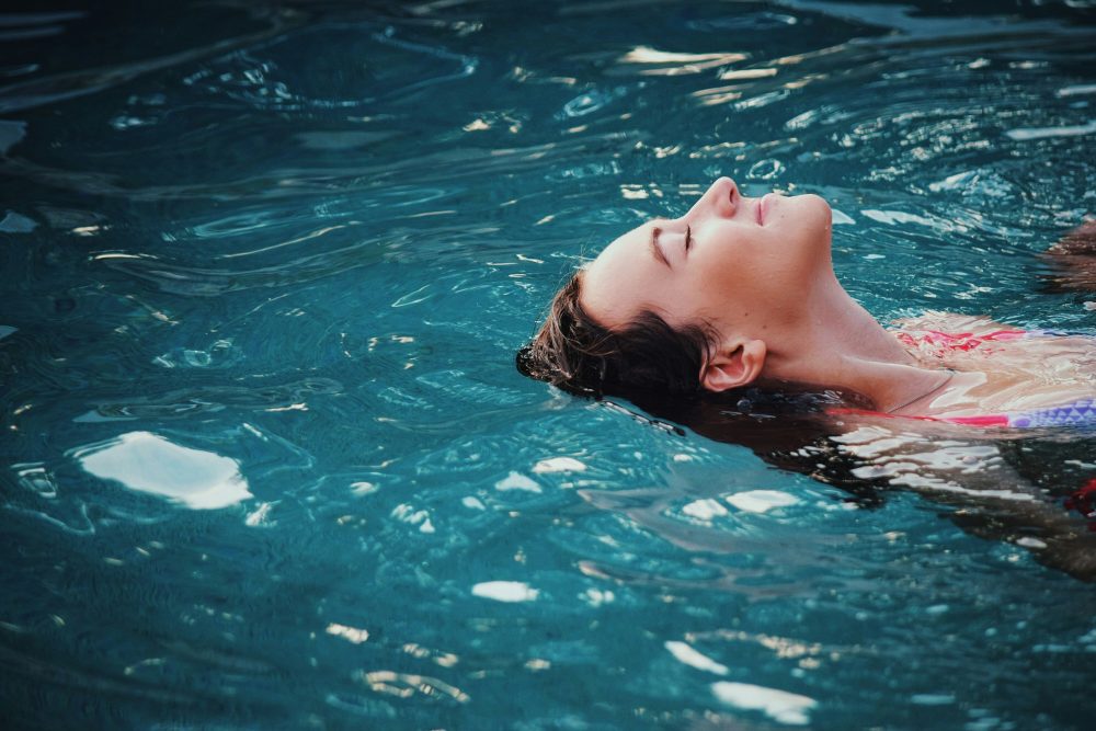 Guest floating on their back, eyes closed, in calm blue water
