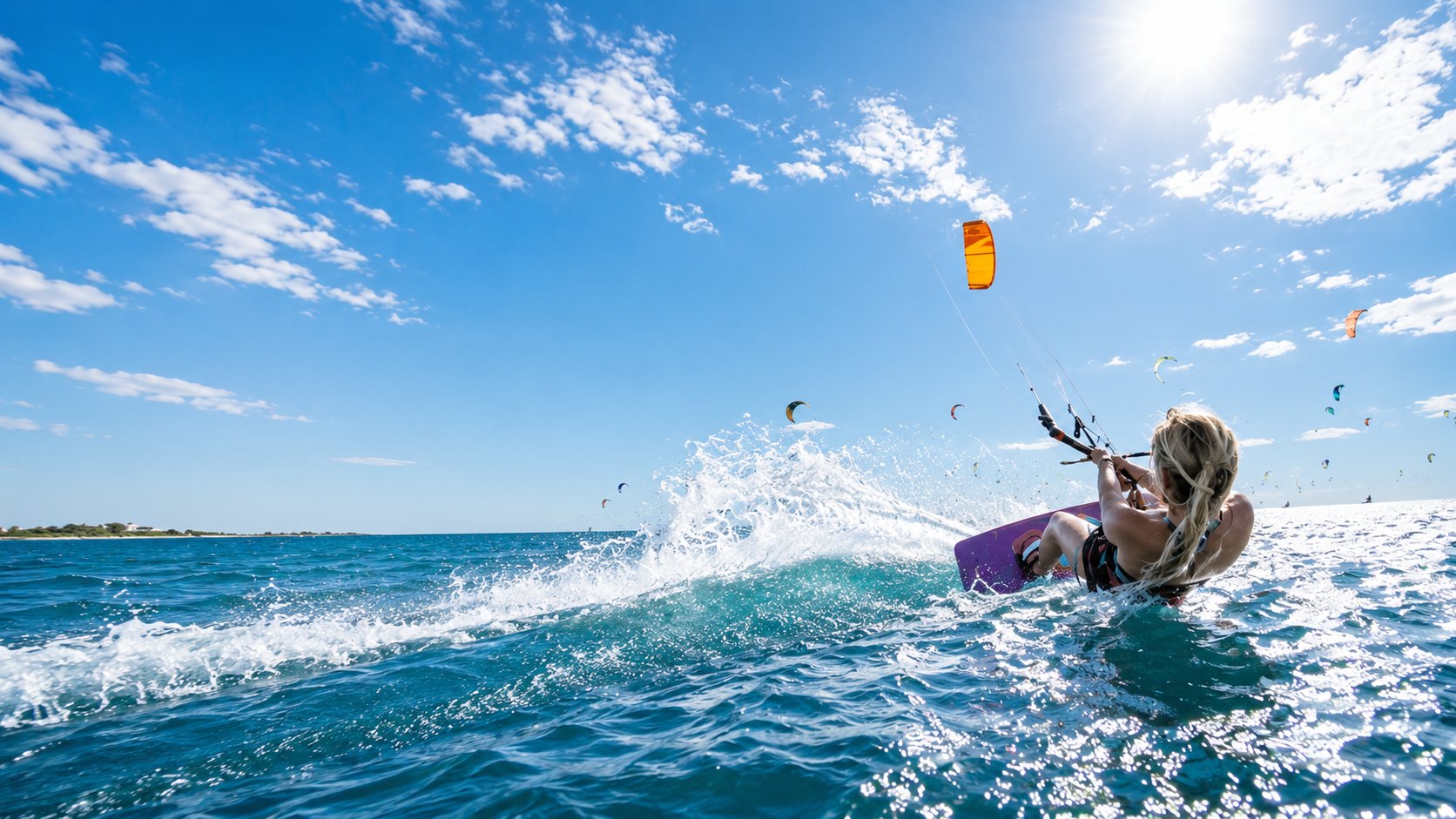 A kitesurfer carving through spray with kites filling the sky behind