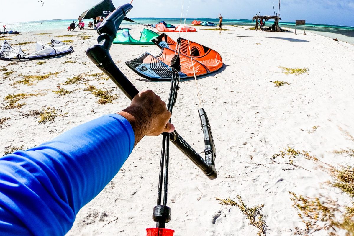 Rider holding a kite bar on the beach with kites pumped up behind
