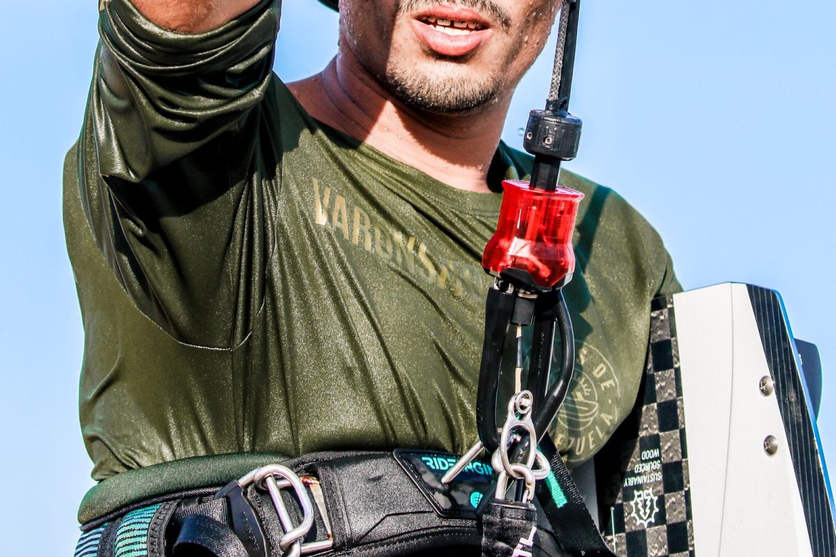 Kitesurfer in a waist harness, hooked in and holding the bar overhead