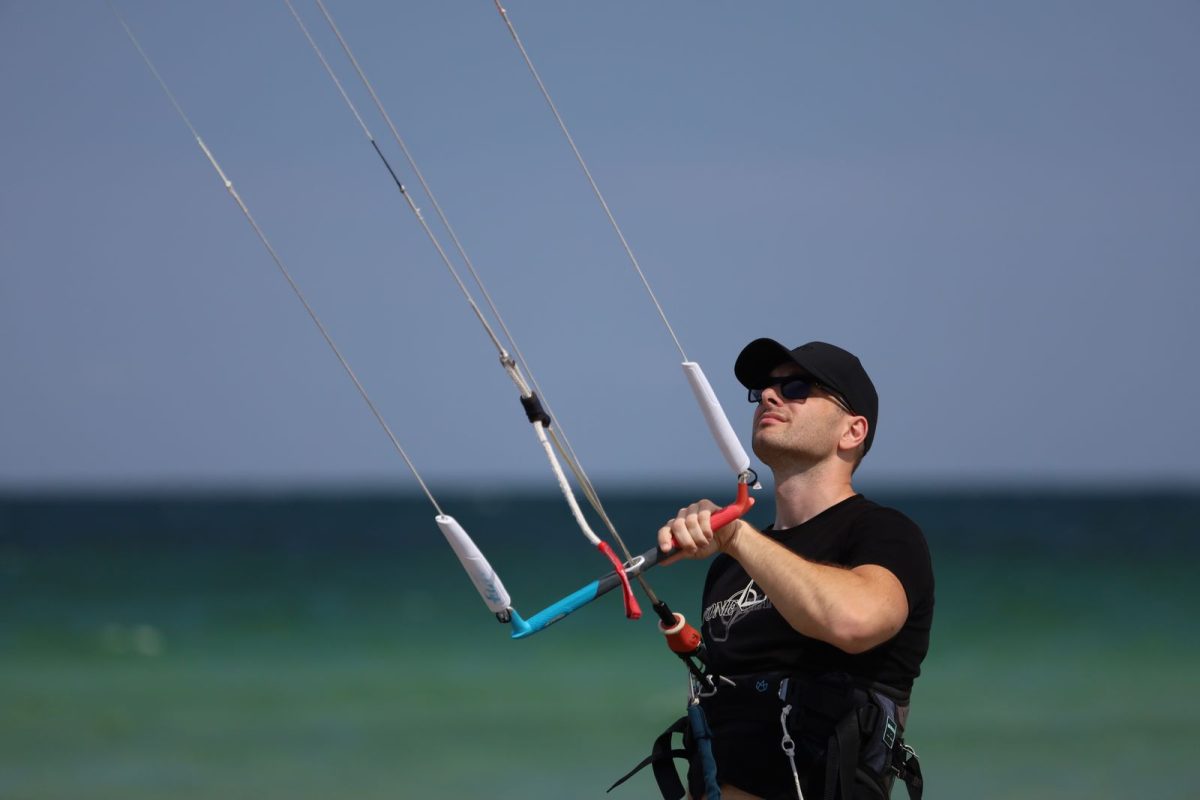 Kitesurfer steering with the control bar, lines running up to the kite