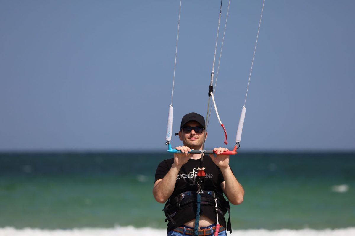 Kitesurfer holding the bar with both hands at the water's edge