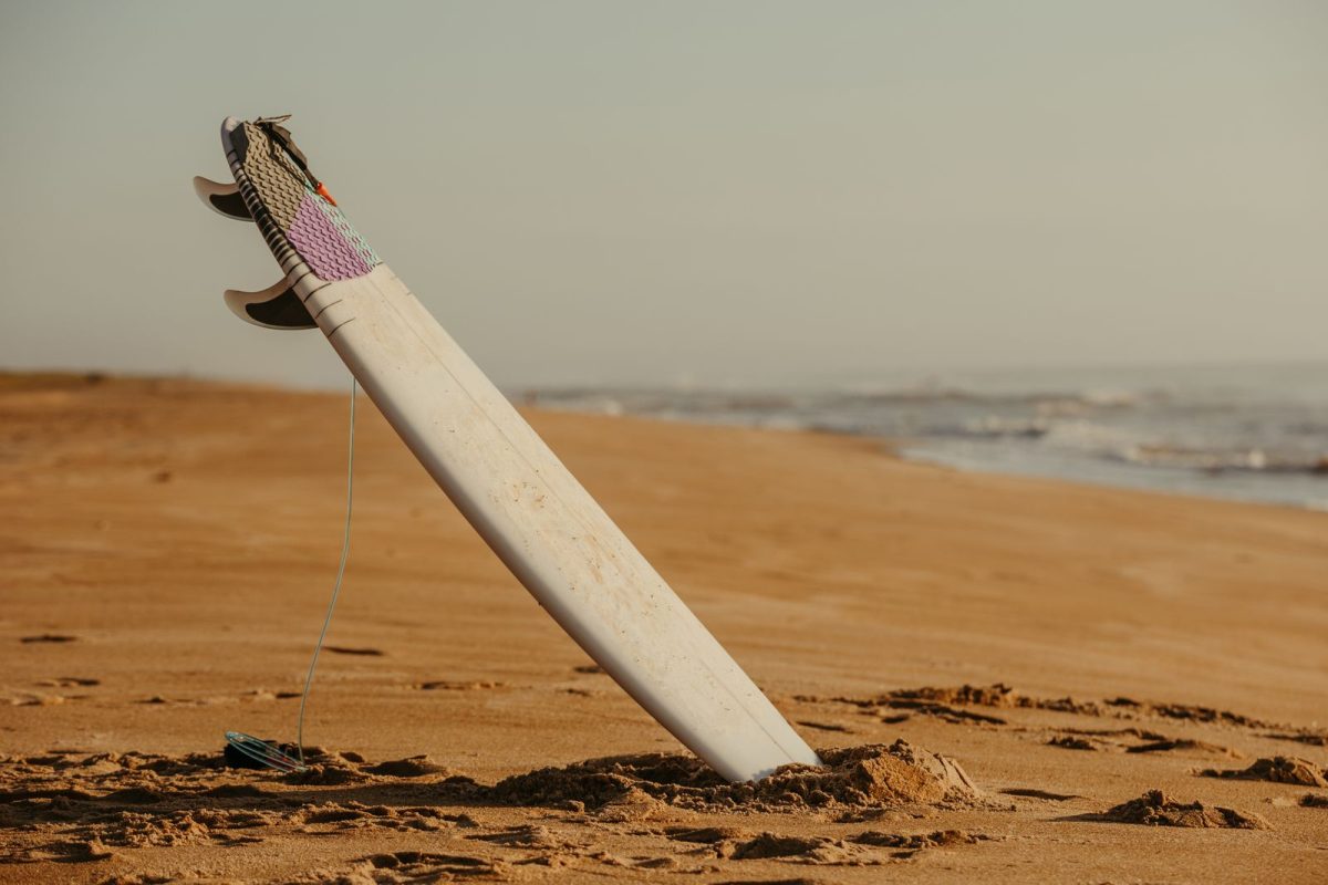 Surfboard standing upright in the sand on an empty beach