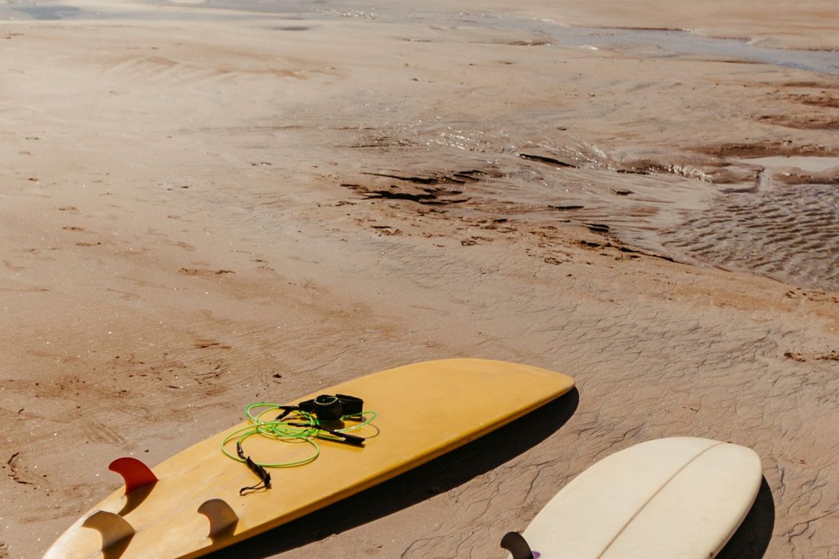 Two surfboards lying on a wide sandy beach