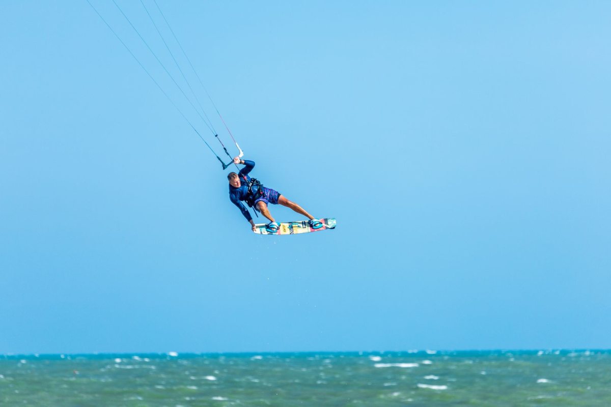 Kitesurfer mid-air above turquoise water, kite and lines overhead