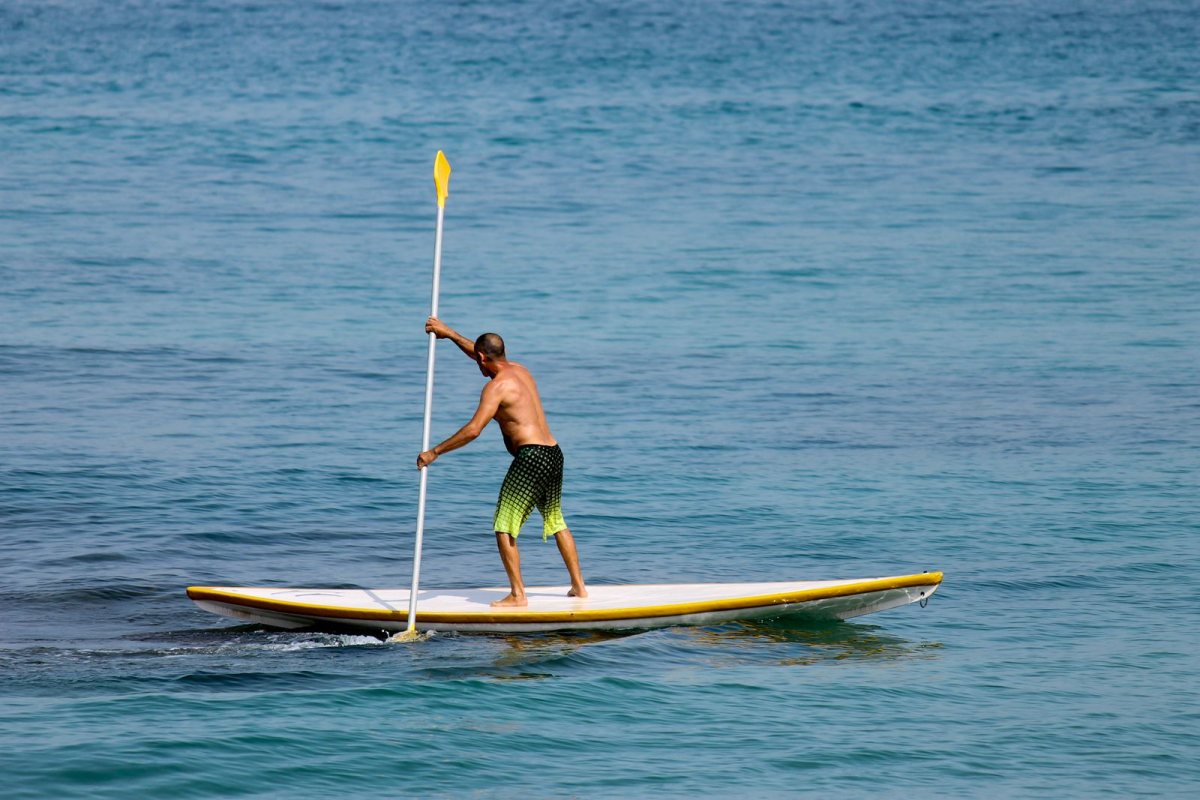 Paddler standing on a stand-up paddleboard on clear turquoise water