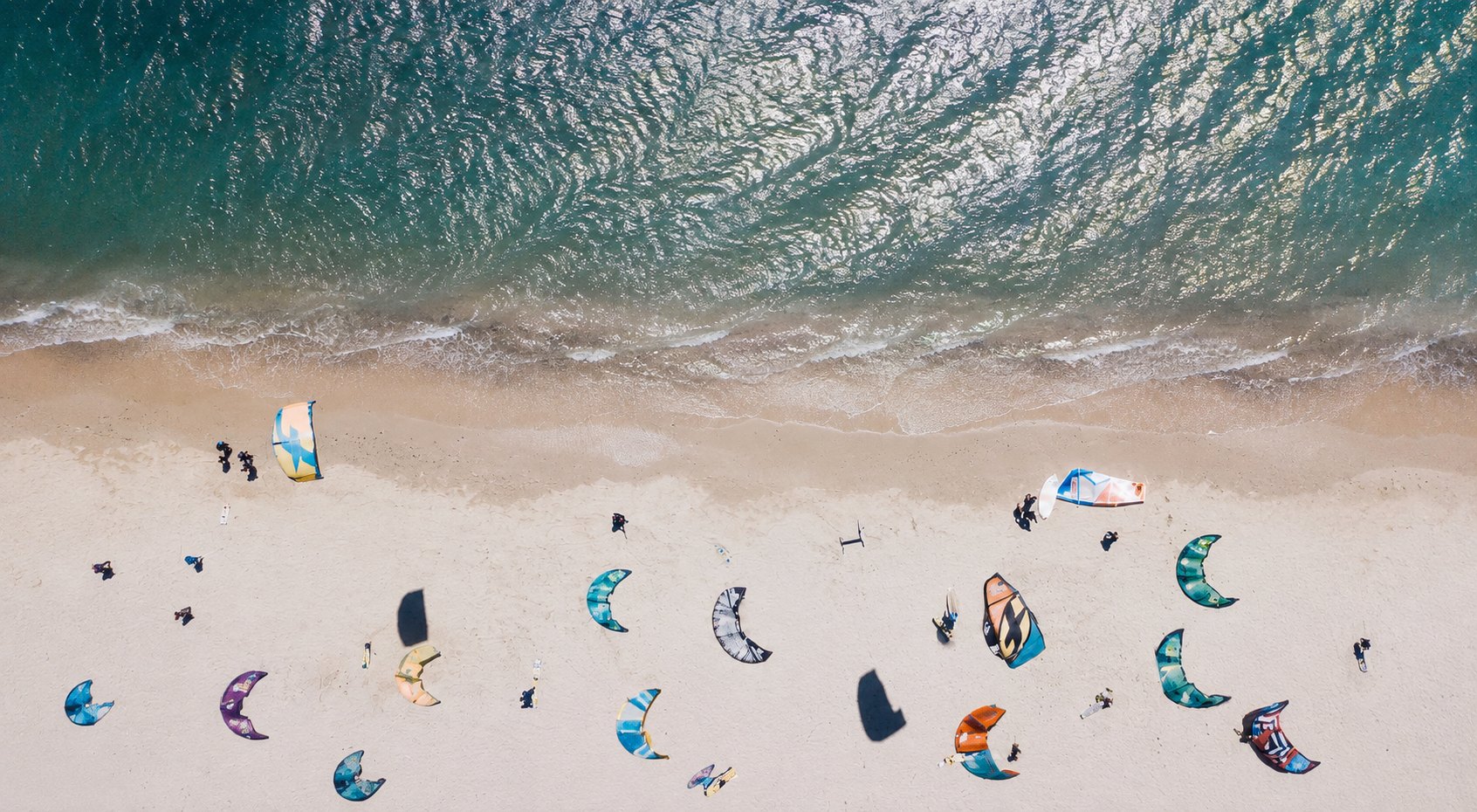 Aerial view of kites laid out on the sand beside the surf at Watamu beach, Kenya